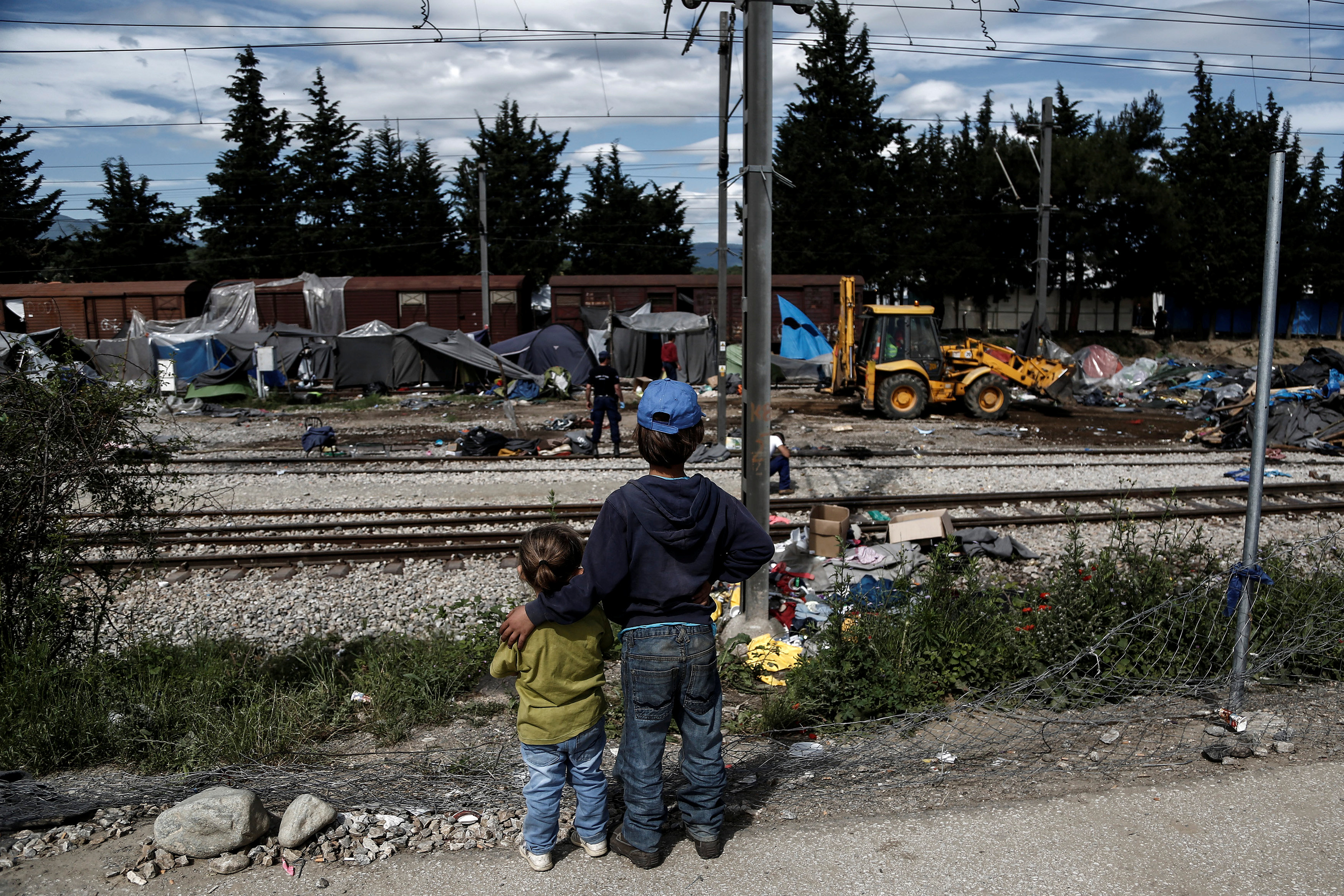  Migrant children look on as a bulldozer removes tents from the train tracks during a police operation at a migrant camp at the border between Greece and Macedonia, near the village of Idomeni 